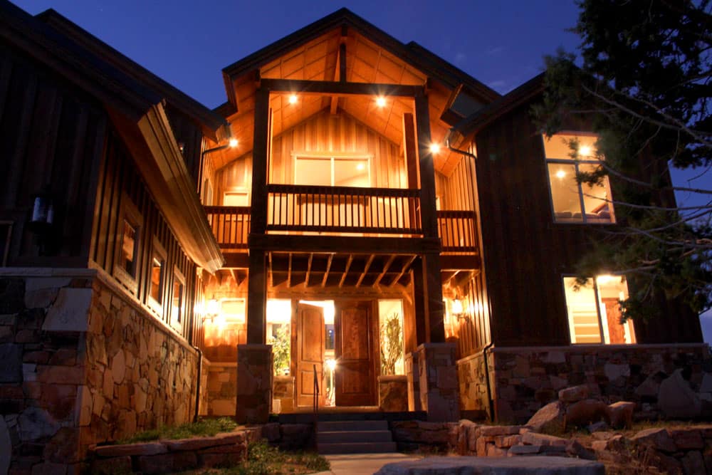 A chalet-style house illuminated at dusk with wooden accents and stone details.
